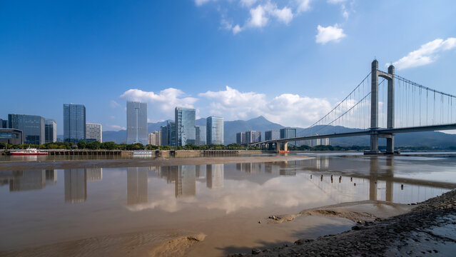 Modern city skyline with suspension bridge over river