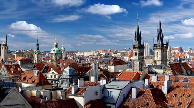 View of rooftops and towers in Prague with blue sky and clouds on a sunny day