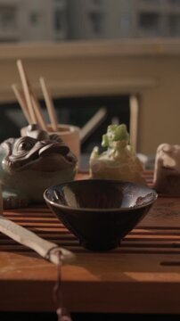 Panning shot of bamboo tea tasting box, glass pitcher, vacuum flask, figurines of tea gods, teabowl and bamboo strainer at tea tray. Traditional chinese gongfu tea ceremony at home balcony