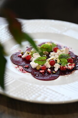 sliced beetroot appetizer on a white plate, goat cheese and fresh herbs, healthy vegetarian food, close-up view, elegant food presentation,
