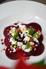 sliced beetroot appetizer on a white plate, goat cheese and fresh herbs, healthy vegetarian food, close-up view, elegant food presentation,