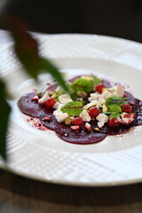 sliced beetroot appetizer on a white plate, goat cheese and fresh herbs, healthy vegetarian food, close-up view, elegant food presentation,