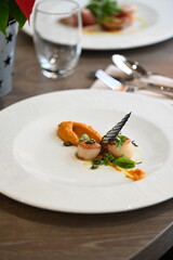 scallops with pumpkin puree, gourmet appetizer, served on a white plate in a restaurant, close-up food photography, elegant fine dining presentation,