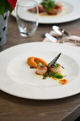 scallops with pumpkin puree, gourmet appetizer, served on a white plate in a restaurant, close-up food photography, elegant fine dining presentation,