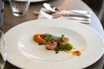 scallops with pumpkin puree, gourmet appetizer, served on a white plate in a restaurant, close-up food photography, elegant fine dining presentation,