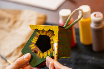 Shallow DOF image of woman painting a small birdhouse arts and crafts concept