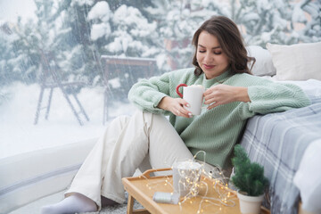 Mindfulness and feel-good moments.  lifestyle portrait smiling  woman with a cup of cocoa resting and spending time at Glamping house  on winter holidays.  mental health.  Christmas holiday dome tent 