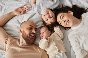 Family joyfully bonding on soft bedding in a cozy home setting filled with love