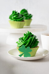 St. Patrick's Day tasty cupcake with green whipped cream decorated clover on white background. Close up. Vertical format.