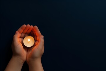 small candle in child hands with flame on dark blue background and right side copy space for condolence mourning remembrance.