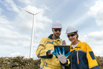 Two wind turbine technicians wearing safety gear analyzing data on tablet in front of wind turbine, symbolizing teamwork, renewable energy, smart field operations.
