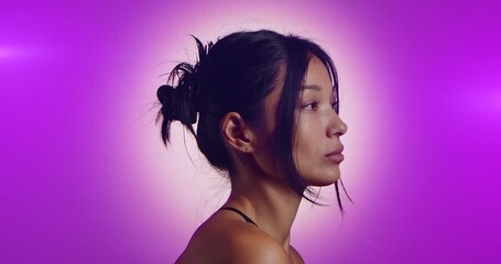 A young Korean model poses in a studio lit by pink neon lights. The concept is beauty, fashion and natural feminine beauty. Slow motion.