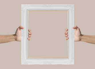 Hands holding empty vintage white photo frame, on soft brown background