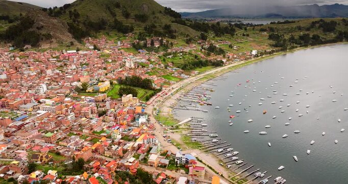 Aerial view of Copacabana, a vibrant lakeside town on Lake Titicaca in Bolivia, showing colourful buildings, boats along the shore, and dramatic Andean landscapes