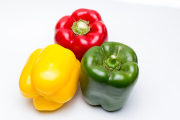 Pimientos morrones rojo, amarillo y verde sobre fondo blanco