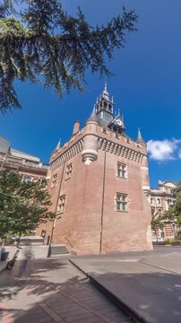 Renaissance dungeon clock tower and classical brick facade of the Capitole timelapse hyperlapse, city hall of Toulouse, France, surrounded by trees in Charles de Gaulle Square under a blue cloudy sky