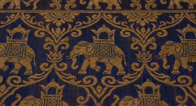 Golden embroidered elephants on dark blue silk fabric with decorative floral scrollwork and ornate patterns