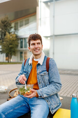 University student eating a healthy salad and relaxing on campus during a break