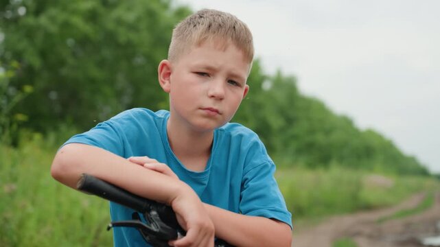 white boy leaning bicycle dirt road, thoughtful gaze toward horizon with hands on handlebars, rural track flanked by green trees, overcast sky and quiet stillness, medium shots convey decision