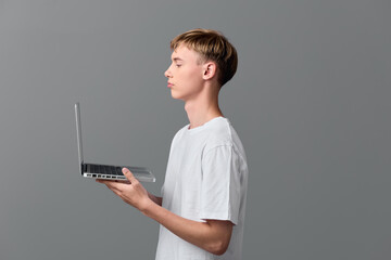 Young man in a white t shirt holds a laptop in profile, showcasing modern technology and digital work, minimal studio background, ideal for remote learning and online collaboration