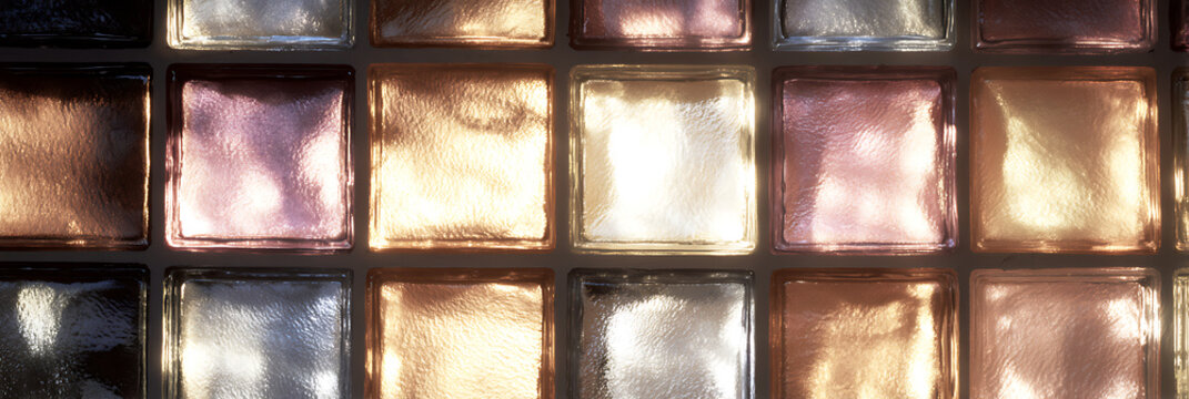 Texture of illuminated glass block wall with warm and cool lighting creating geometric grid pattern with purple gold and silver tones for architectural background