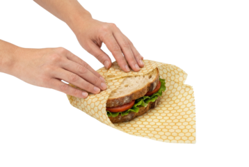 Hands wrapping sandwich in reusable food wrap