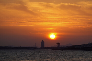 Distant Lighthouse Under Fiery Sunset Sky