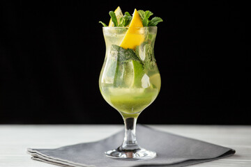 Mint lemon cocktail with lime in tall glass on black background