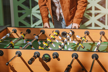 Player's hands gripping rods of a foosball table, moving players in a competitive and fun indoor...