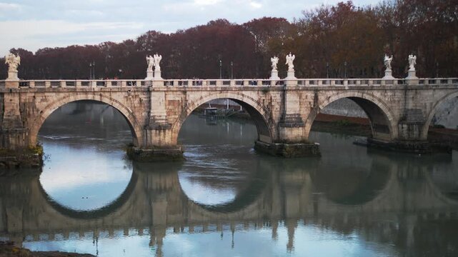 The iconic Ponte Sant�Angelo spans the Tiber River near Castel Sant�Angelo. Passersby and tourists stroll along the bridge, capturing the historic beauty of Rome in winter.
