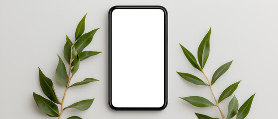 Top view of smartphone with blank screen and green leaves on gray background representing technology, eco lifestyle, and modern minimal design.