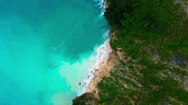 Drone footage of Stunning aerial seascape where emerald cliffs blend with calm turquoise sea in sine beach, Tulungagung, East Java, Indonesia