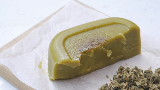 Close up shot of cannabis-infused butter (cannabutter) and a spatula on parchment paper, medicinal and edible marijuana concept.