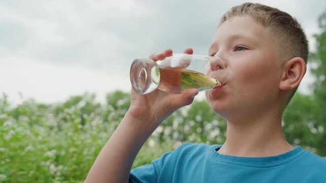 white boy sipping drink in meadow, overcast sky and wildflowers, glass jar held close, curious tasting and thoughtful expression, backyard picnic scene, youthful innocence and gentle breeze, quiet