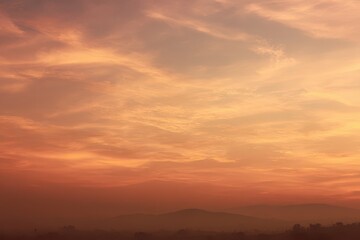 Calm horizon bathed in golden hour haze and sunlit clouds