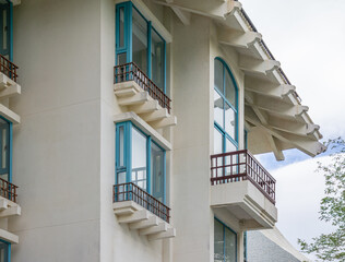 Modern white building facade with blue window frames and balconies in asian style architectural details of residential house or hotel under bright sky minimalist exterior design.