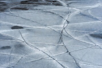 Skate marks on reflective frozen ice surface in winter