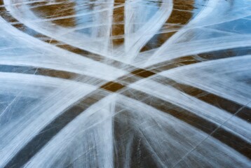 Ice skating marks on frozen rink surface in winter light