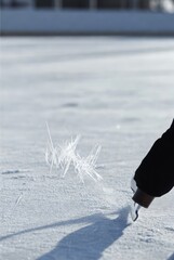 Ice skater carving frozen rink surface in winter sunlight