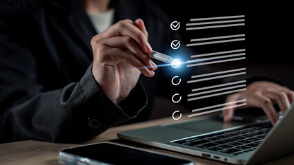 Hand using a stylus to check off items on a glowing digital checklist over a laptop, symbolizing online audit, digital marketing tasks, data review, and organized business workflow.