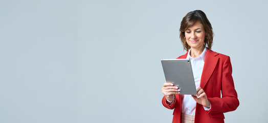 Focused middle aged businesswoman using touchscreen pc for office investment work. Mature ceo...