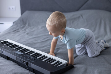 Curious little boy looking with interest at piano keys.