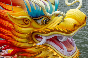 Close up of traditional chinese dragon head in yellow and red colors on water decorative figure for dragon boat festival or lunar new year celebration oriental mythology and culture art.