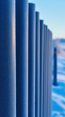 Obraz premium A close-up view of blue poles aligned in a snowy landscape against a clear sky backdrop