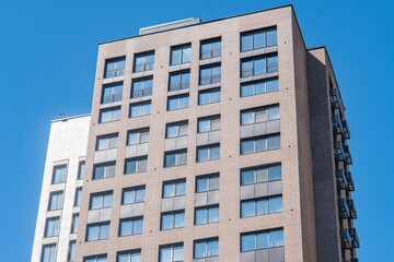 Fototapeta premium Modern high-rise building in a city, blue sky with scattered clouds, contemporary architectural style, balconies and windows, rectangular shapes, grid pattern, daytime, sunlight reflection, shadows,