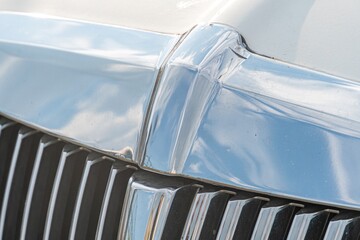 Close-up view of a slightly damaged limousine grille with reflective chrome emblem and metal bars a