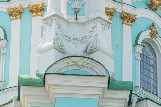 A grand, opulent, green and white architectural structure with gold accents The facade is adorned with intricate molding and two protective statue flankers at the central archway Soft shadows sugge