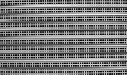 Gray steel Roller Shutter Door Background with sunlight shadow on surface corrugated Grey metal mesh curtain door entrance to store Perforated gray silver iron Garage Security door background backdrop