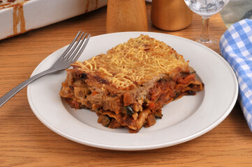 Part de lasagnes aux l&eacute;gumes maison servie dans une assiette avec une fourchette en gros plan servie &agrave; table