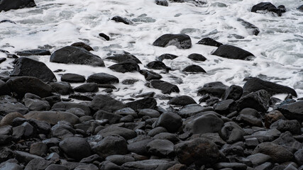 Obraz premium Nahaufnahme eines Strandes mit schwarzem Kiesel und Wasser